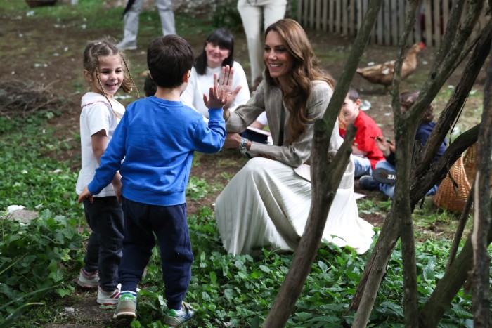 La principessa del Galles Kate Middleton nell'area verde del nido d'infanzia comunale Salvator Allende di Reggio Emilia batte il cinque a un bambino - ph. Andrew Parsons / Kensington Palace